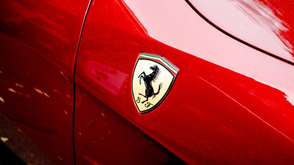 Un primo piano dettagliato dell'iconico emblema Ferrari su un'auto di lusso.